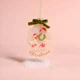 A personalized Christmas ornament shaped like a snowman with two baby swans, a green velvet bow, and the text 'BABY'S FIRST Christmas' on a soft pink background.