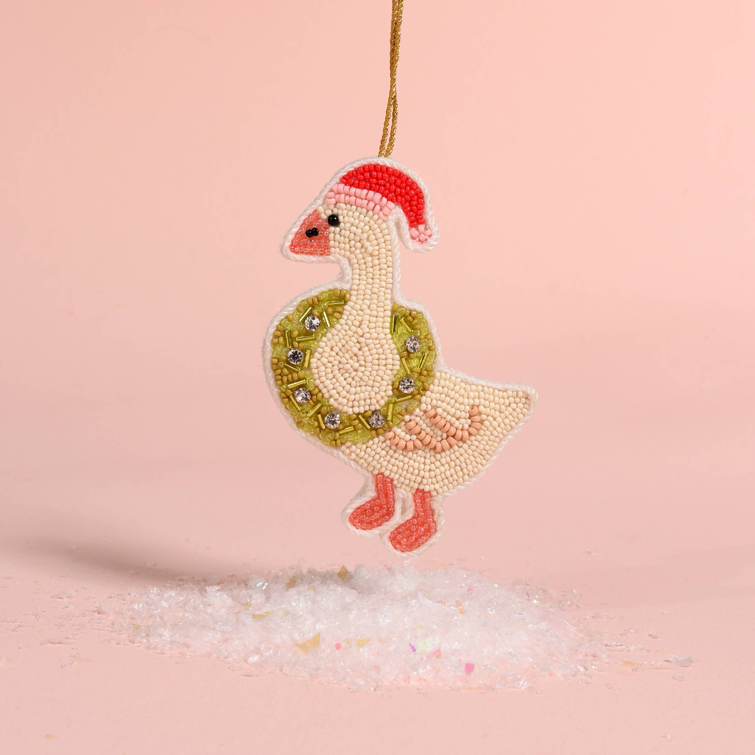 Decorative goose ornament with a wreath and Santa hat on a pink background