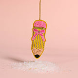 Beaded pencil ornament with a pink bow on a pink background