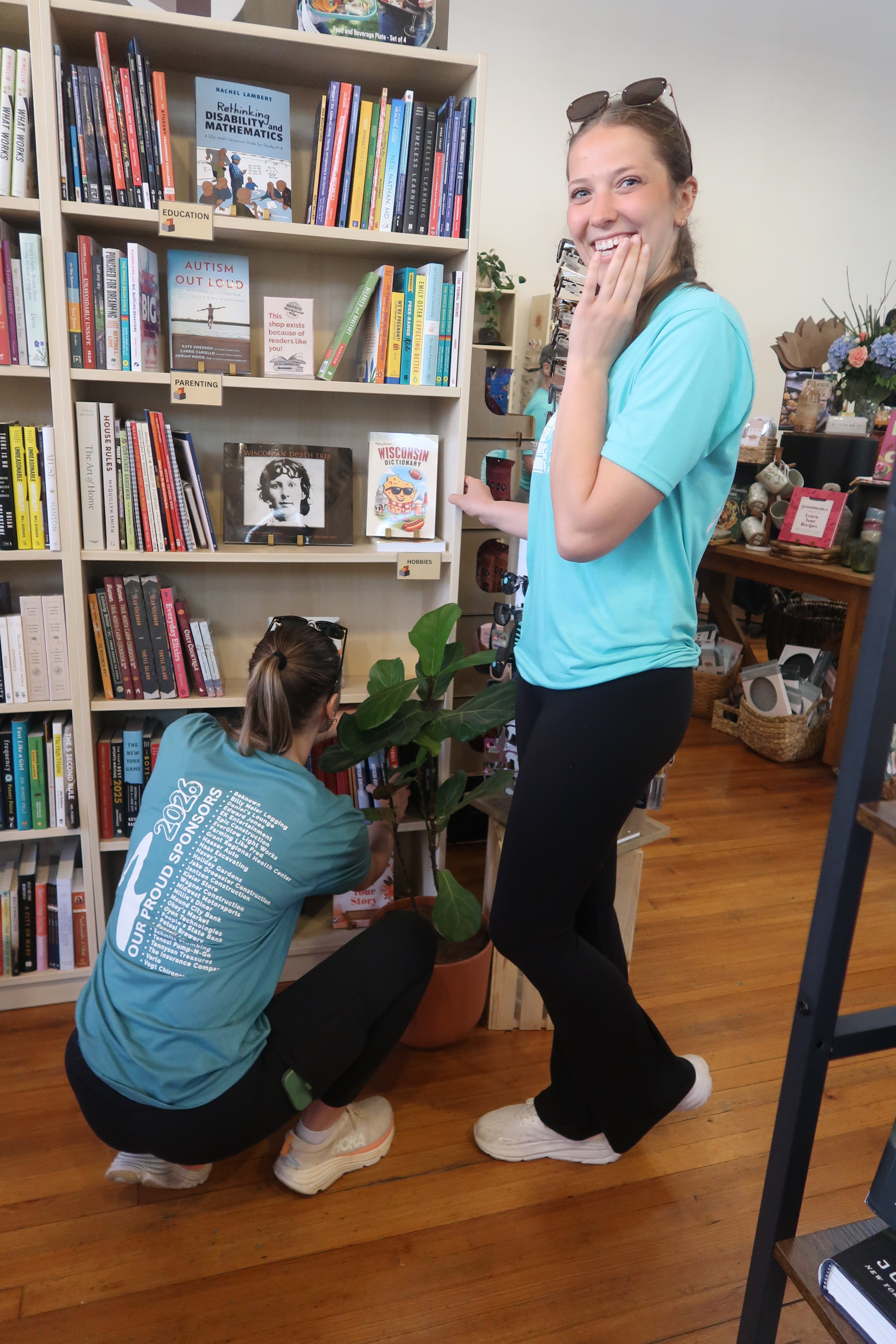 Two women organizing books in a home library.