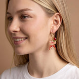 Close-up of a woman wearing a unique earring with a decorative design on a beige background