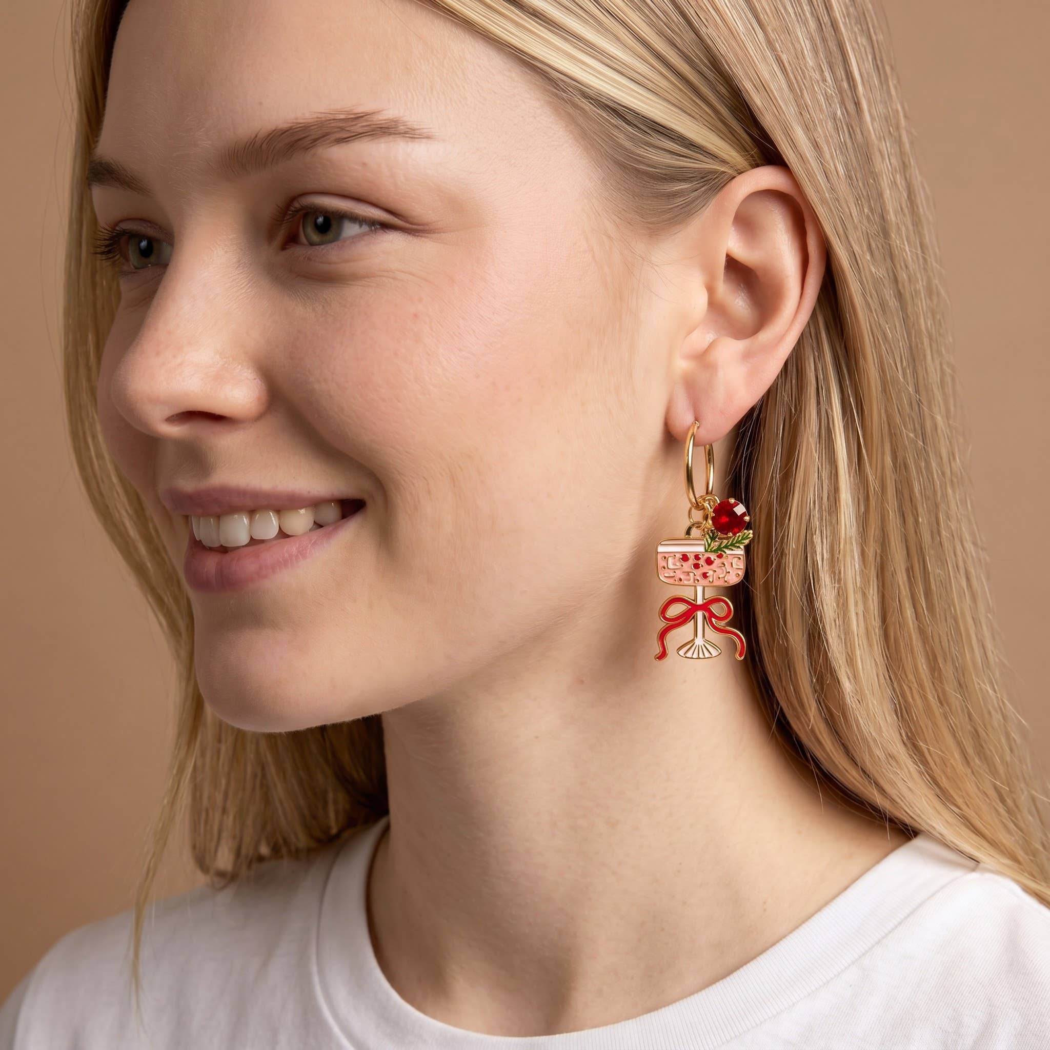 Close-up of a woman wearing a unique earring with a decorative design on a beige background