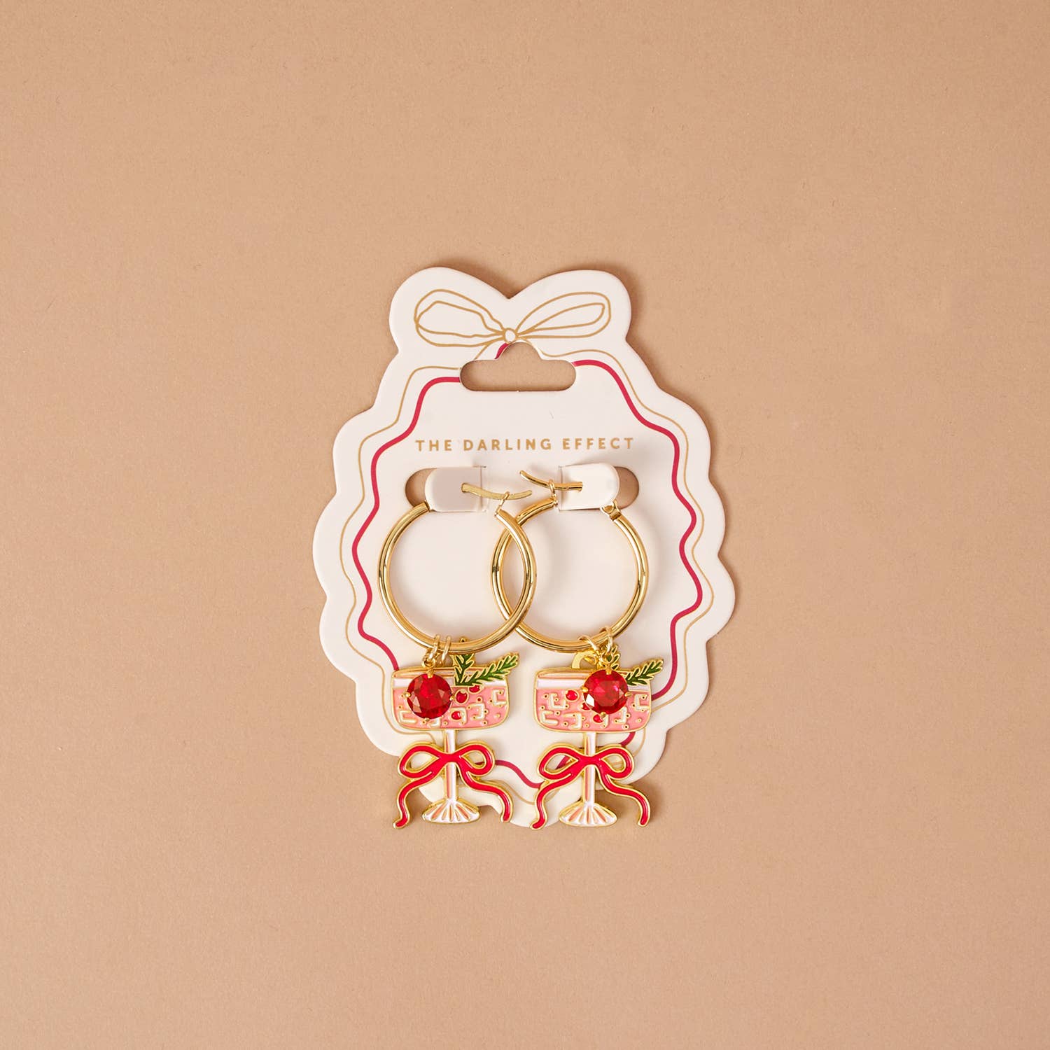 Pair of earrings in a 'The Darling Effect' packaging on a beige background