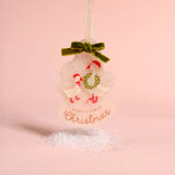A personalized Christmas ornament shaped like a snowman with two baby swans, a green velvet bow, and the text 'BABY'S FIRST Christmas' on a soft pink background.