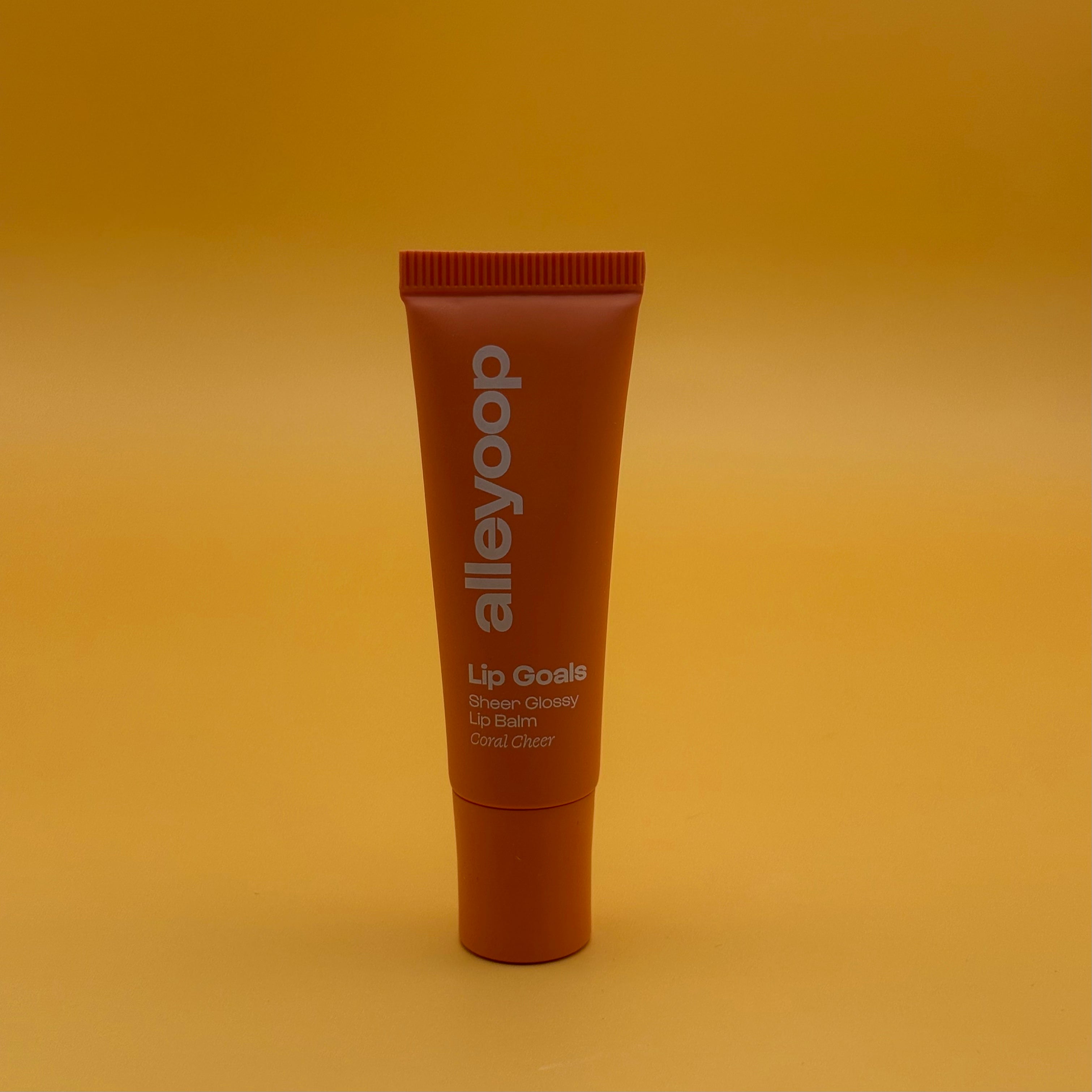 Lip balm tube with 'alleyoop' branding on a yellow background