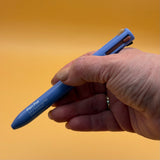 Hand holding a blue alleyoop pen pal make a mauve color against an orange background