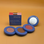 Makeup product set with three compact cases and a mirror on an orange background, featuring the brand 'alleyoop'.