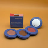 Makeup product set with three compact cases and a mirror on an orange background, featuring the brand 'alleyoop'.