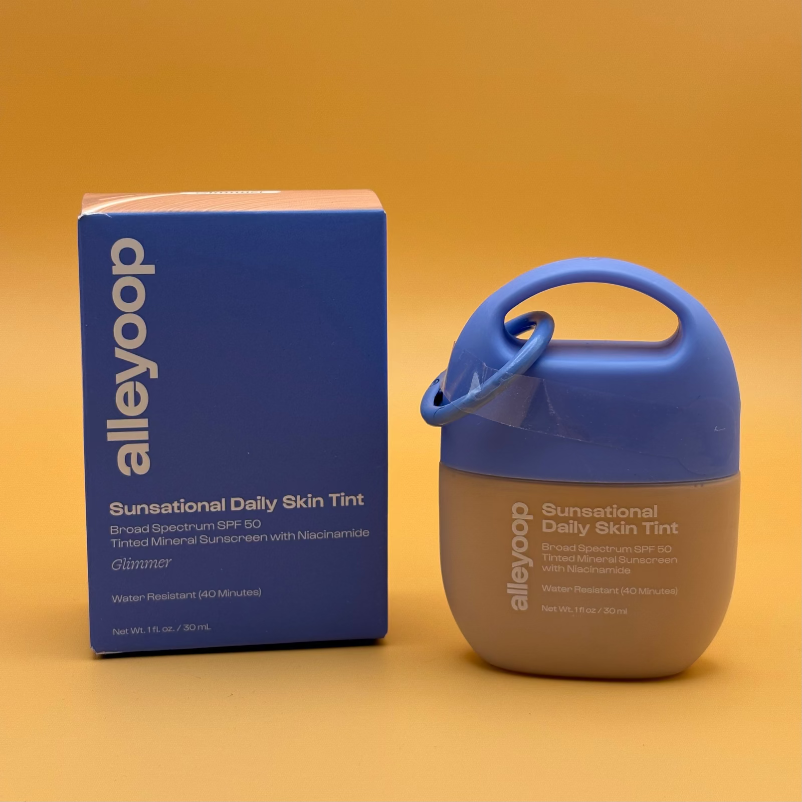 Alleyoop Sun sensational Daily Skin Tint glimmer with blue lid and packaging on a yellow and orange background