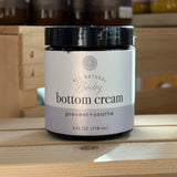 Jar of Rowe Casa all-natural baby bottom cream on a wooden surface