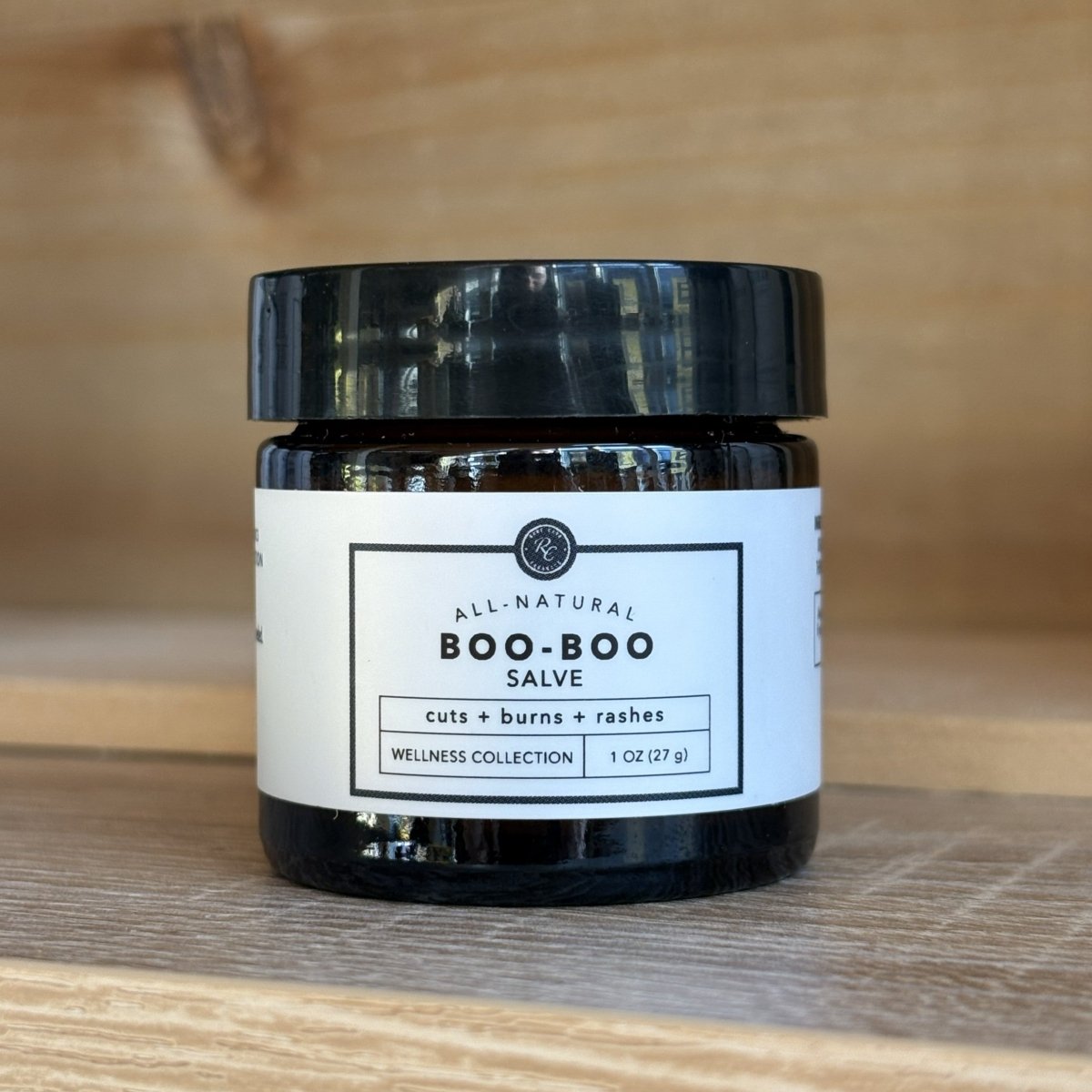 Jar of Rowe Cosa all-natural boo-boo salve on a wooden surface