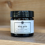 Jar of Rowe Cosa all-natural boo-boo salve on a wooden surface