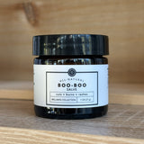 Jar of Rowe Cosa all-natural boo-boo salve on a wooden surface