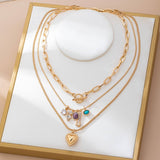 Gold-tone layered necklace with mixed chain and gem charm cluster