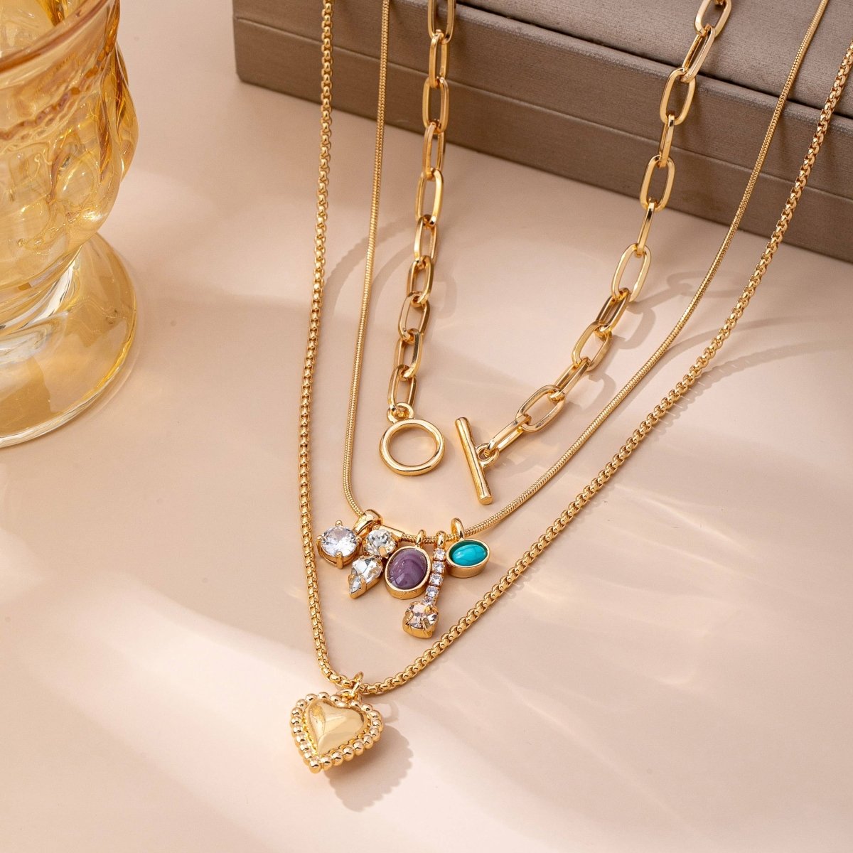 Gold-tone layered necklace with mixed chain and gem charm cluster