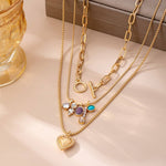 Gold-tone layered necklace with mixed chain and gem charm cluster