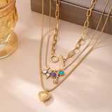 Gold-tone layered necklace with mixed chain and gem charm cluster