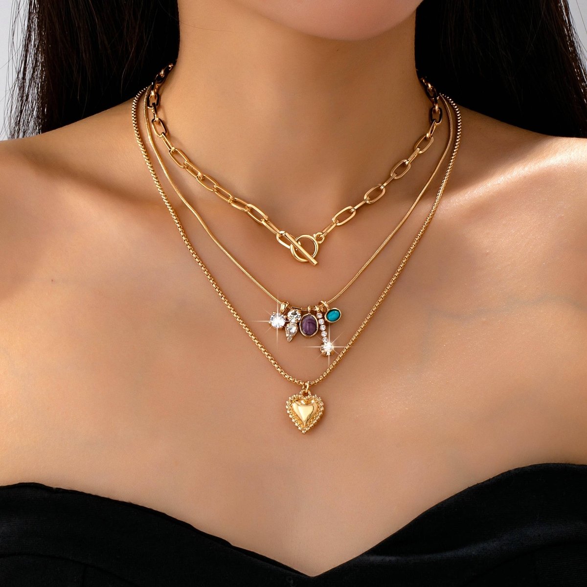 Gold-tone layered necklace with mixed chain and gem charm cluster