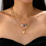 Gold-tone layered necklace with mixed chain and gem charm cluster