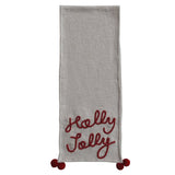 A cotton slub table runner with pom pom trim and Holly Jolly embroidery