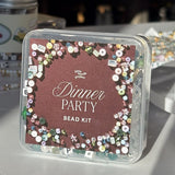 Dinner Party bead kit packaging with decorative beads on a blurred background
