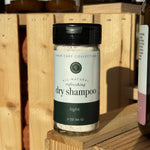 Jar of rowe casa dry shampoo on a wooden shelf. 