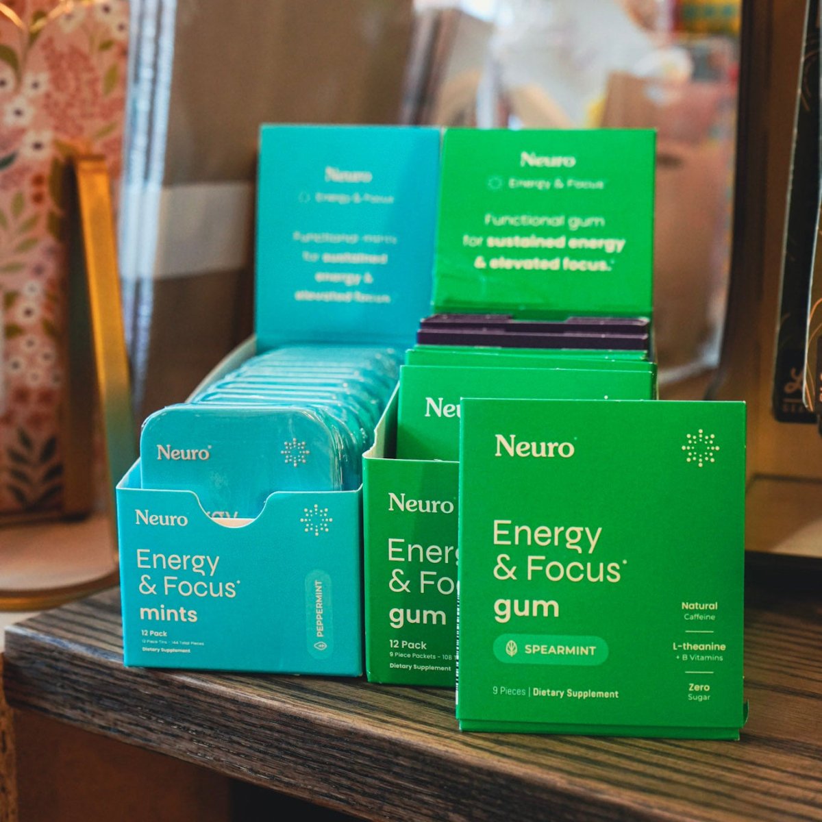 Neuro Energy & Focus mints and gum packaging on a wooden surface with a blurred background.