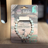 Bracelet packaging with penguin illustration and 'fahlo' branding on a wooden surface