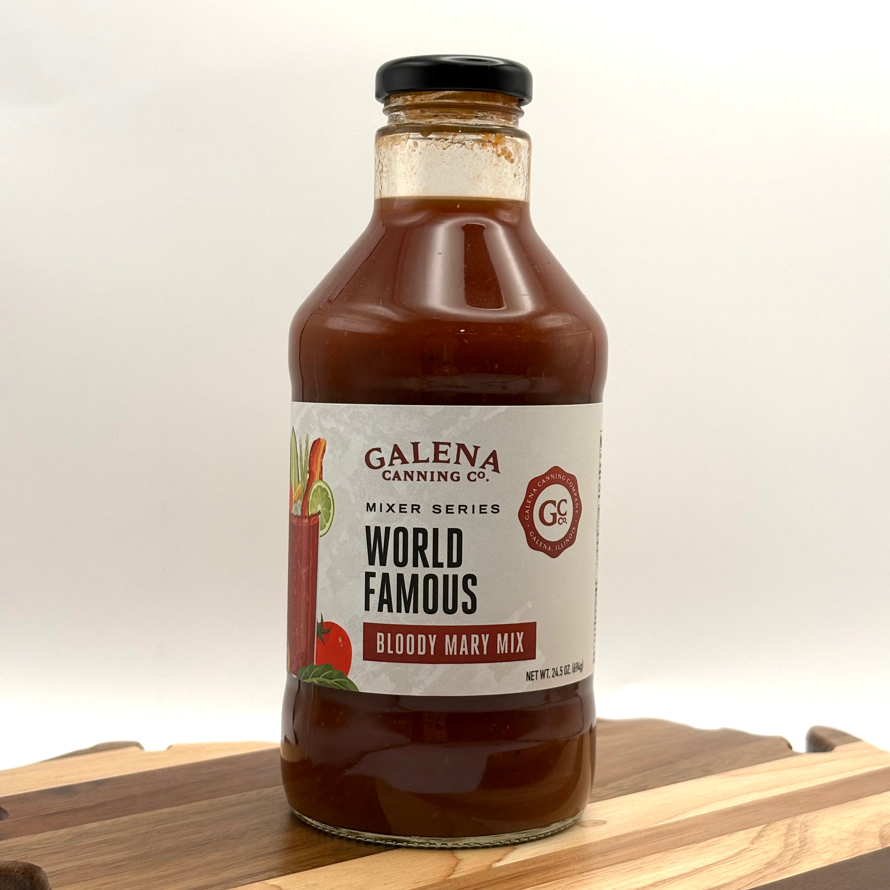 Bottle of Galena Canning Co. World Famous Bloody Mary Mix on a wooden surface with a white background