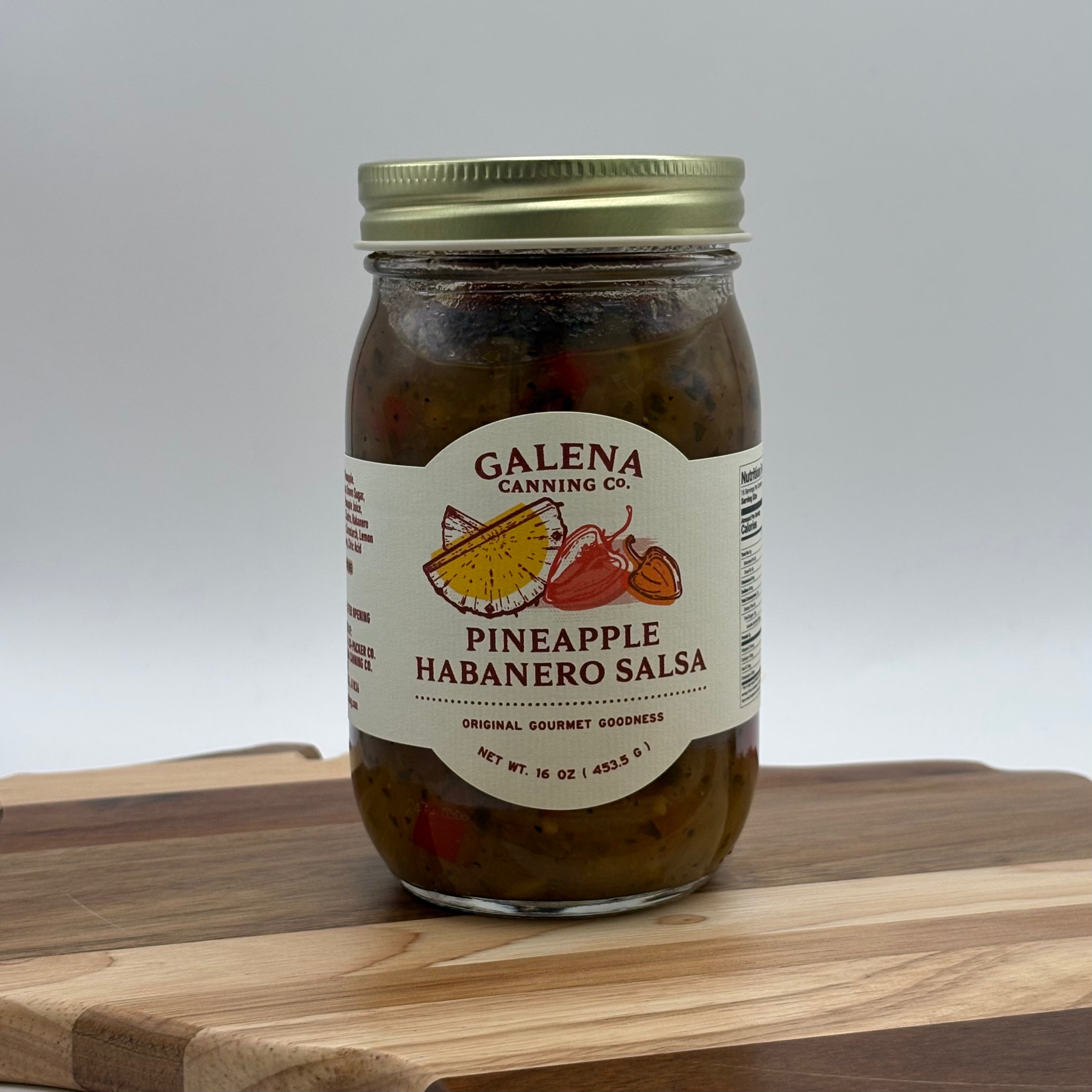 Jar of Pineapple Habanero Salsa with Galena Canning Co. label on a wooden surface.