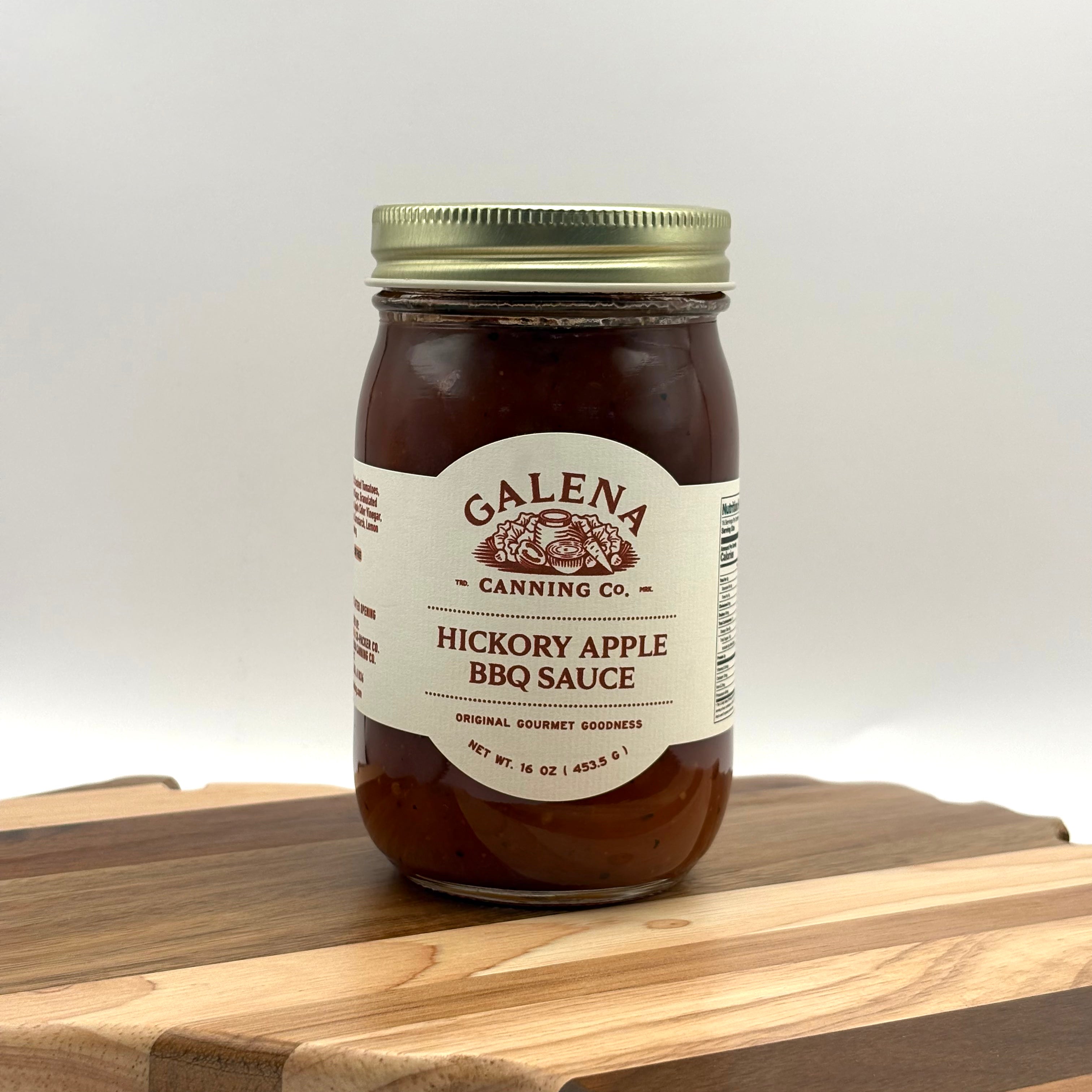 Jar of Galena Canning Co. Hickory Apple BBQ Sauce on a wooden cutting board with a white background