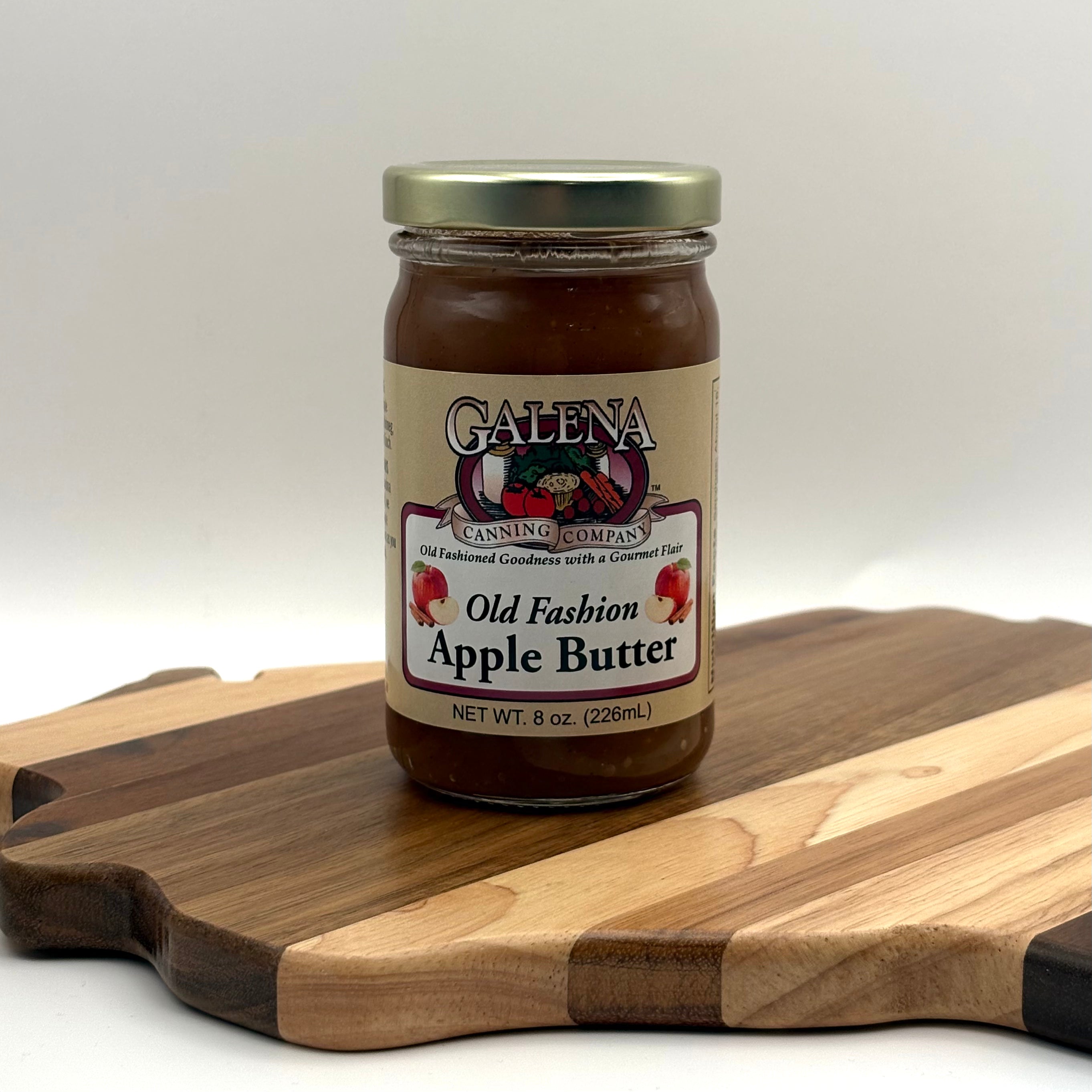 Jar of Galena Canning Company Old Fashion Apple Butter on a wooden cutting board with a white background