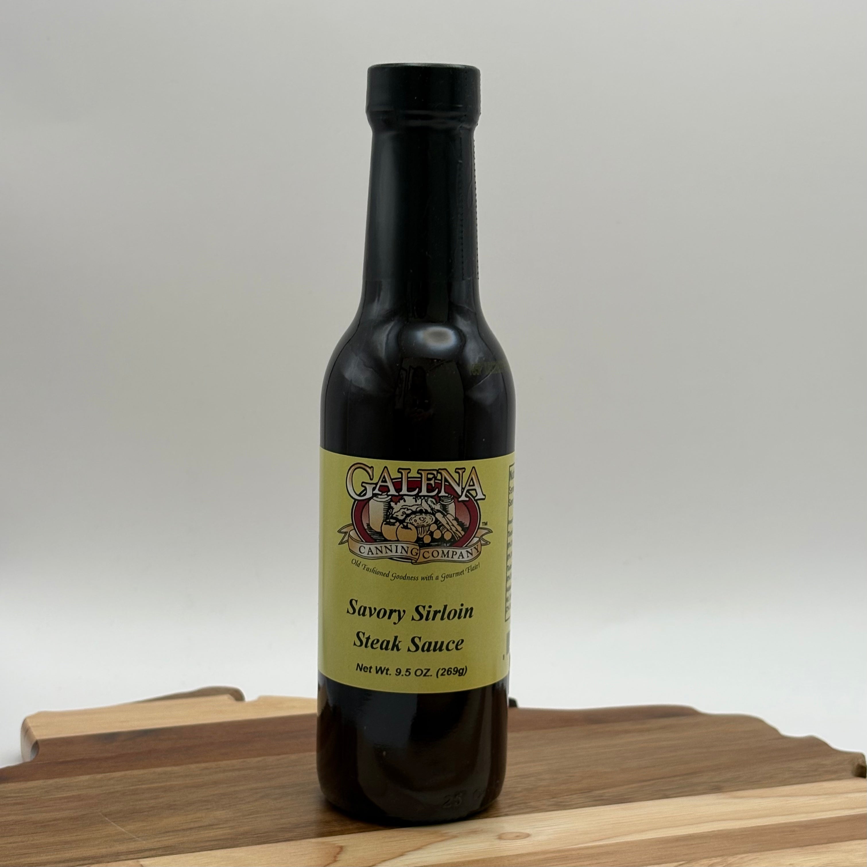 Bottle of Galena Canning Company savory sirloin steak sauce on a wooden cutting board with a white background