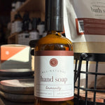 Bottle of all-natural hand soap labeled 'Immunity' on a wooden surface with a blurred background.