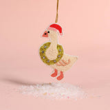 Decorative goose ornament with a wreath and Santa hat on a pink background