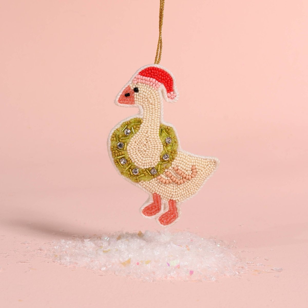 Decorative goose ornament with a wreath and Santa hat on a pink background