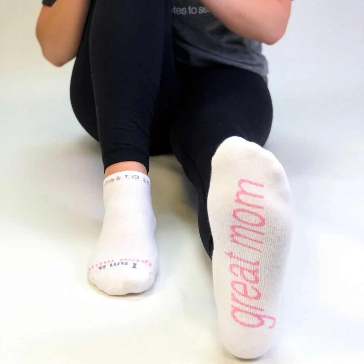 Person wearing white socks with 'great mom' text on a light background