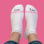 White socks with 'I am beautiful' text on a pink background