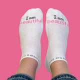 White socks with 'I am beautiful' text on a pink background