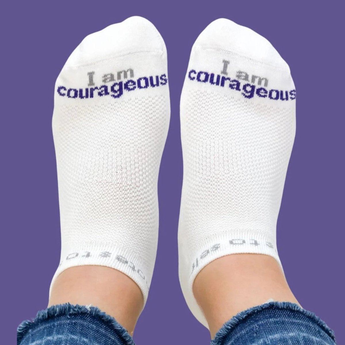 White socks with 'I am courageous' text on a purple background