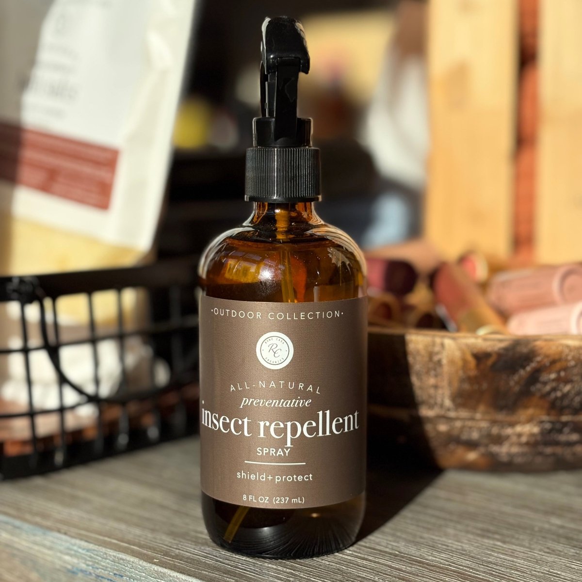Bottle Rowe Casa Natural Insect Repellent Spray on a wooden surface with a blurred background. 
