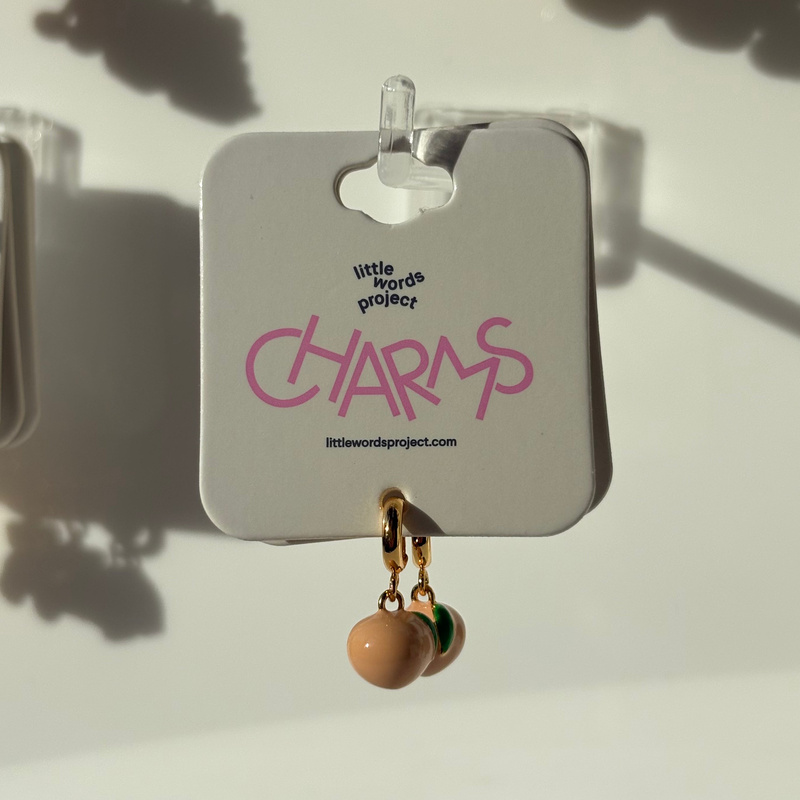 Earrings on a peach 'little words project' card with a beige background