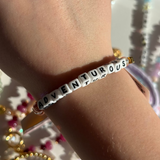 Little Words Project Bracelet with 'ADVENTUROUS' on a wrist against a blurred background