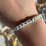 Little Words Project Bracelet with 'BALANCE' beads on a wrist against a blurred background