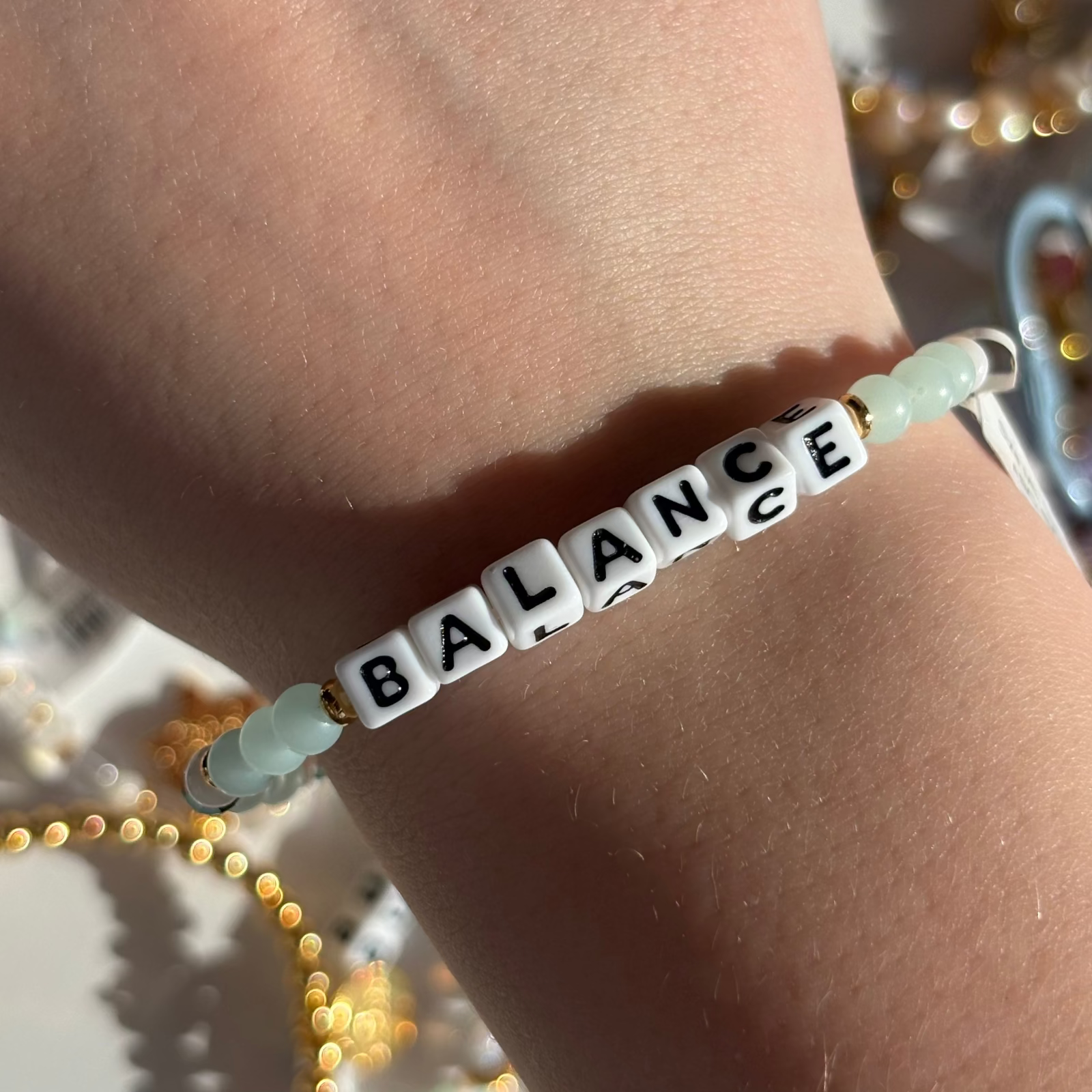 Little Words Project Bracelet with 'BALANCE' beads on a wrist against a blurred background