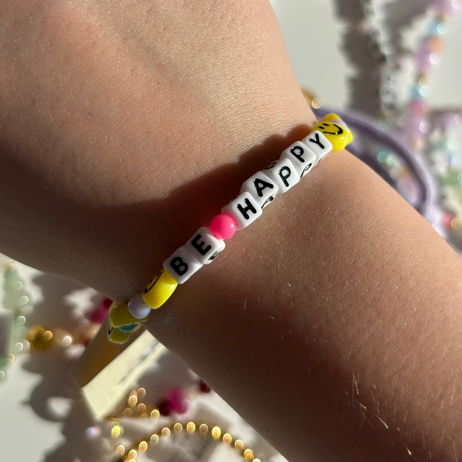 Little Words Project Bracelet with 'BE HAPPY' message on wrist with colorful beads