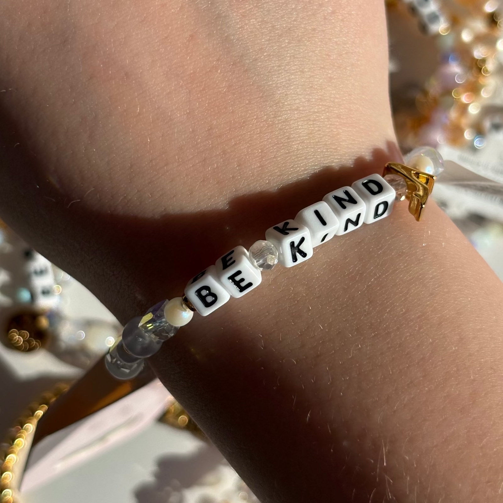 Little Words Project Bracelet with 'BE KIND' beads on a wrist against a blurred background