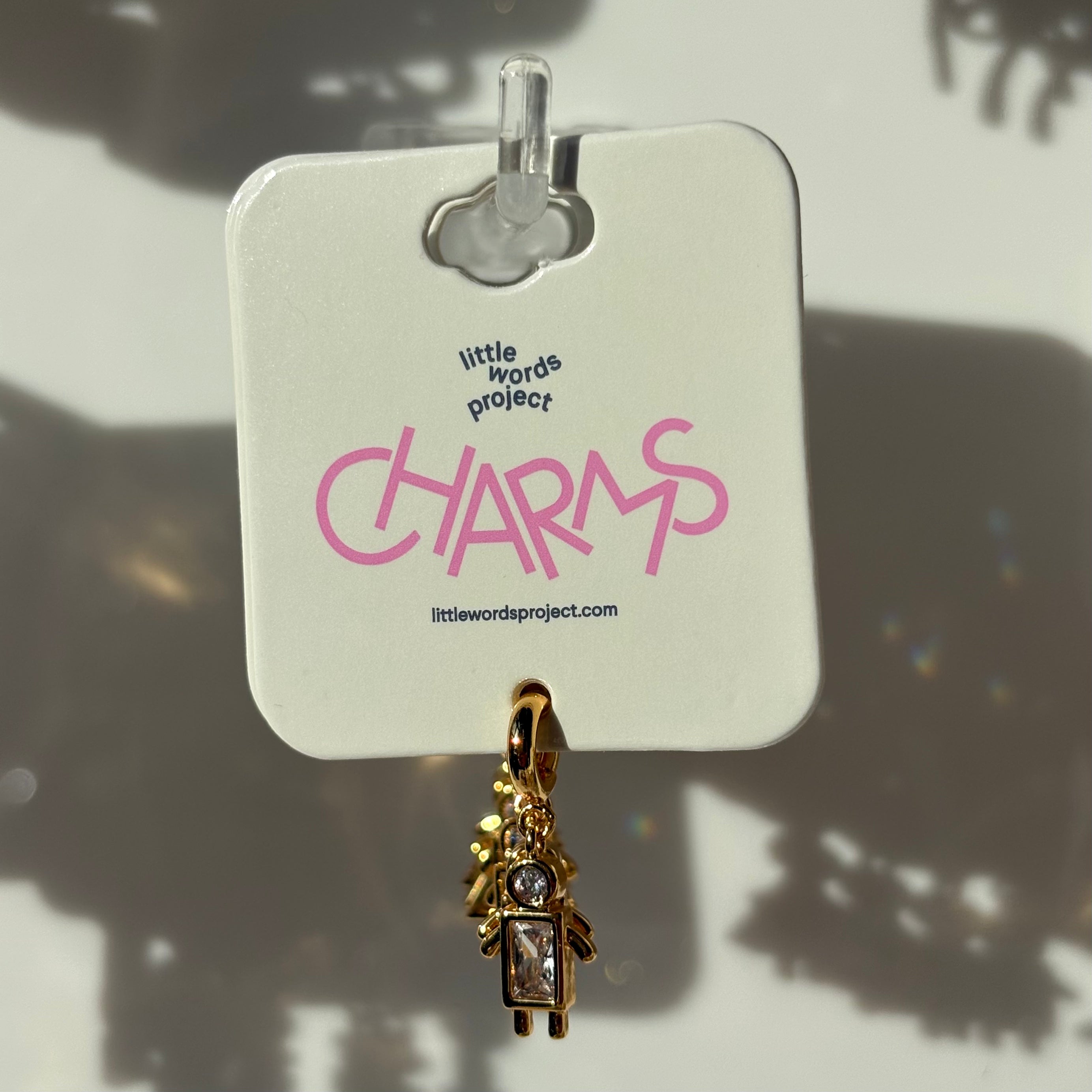 Gold boy charm on a 'little words project' tag with pink text