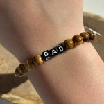 Little Words Project Bracelet with 'DAD' beads on a wrist against a neutral background