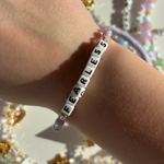 Little Words Projects Bracelet with 'FEARLESS' beads on a wrist against a glittery background